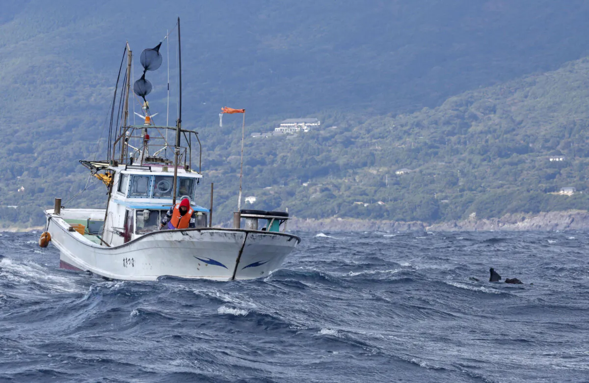 An object believed to belong to the U.S. military aircraft V-22 Osprey that crashed into the sea floats next to a fishing boat at the sea off Yakushima Island, Kagoshima prefecture, western Japan, on Nov. 30, 2023. (Kyodo via Reuters)
