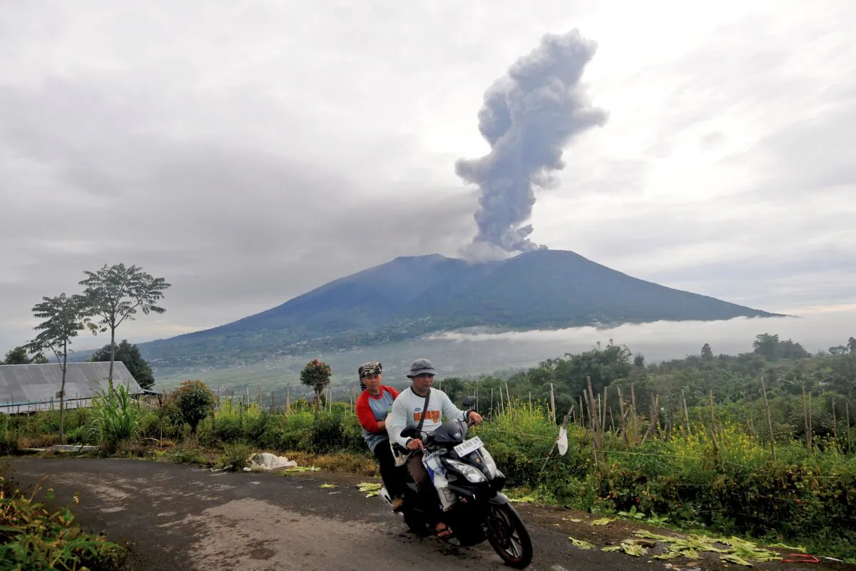 Motorists ride past by as Mount Marapi spews volcanic materials during its eruption in Agam, West Sumatra, Indonesia, on Dec. 4, 2023. (Ardhy Fernando/AP Photo)