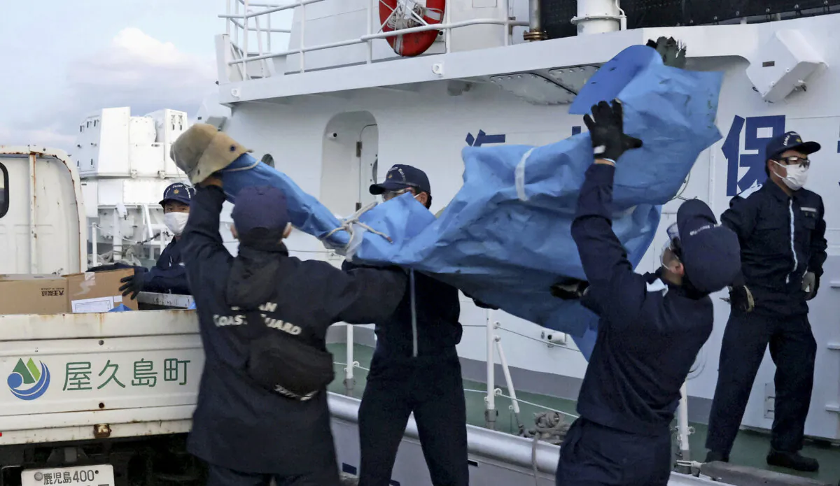 The members of Japanese Coast Guard carry the debris which are believed to be from the crashed U.S. military Osprey aircraft, at a port in Yakushima, Kagoshima prefecture, southern Japan, on Dec. 4, 2023. (Kyodo News via AP)