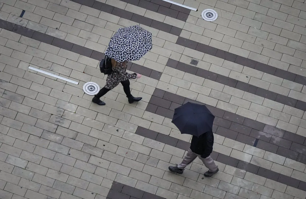 Pedestrians carry umbrellas as light rain falls in Surrey, B.C., on Oct. 21, 2022. (The Canadian Press/Darryl Dyck)