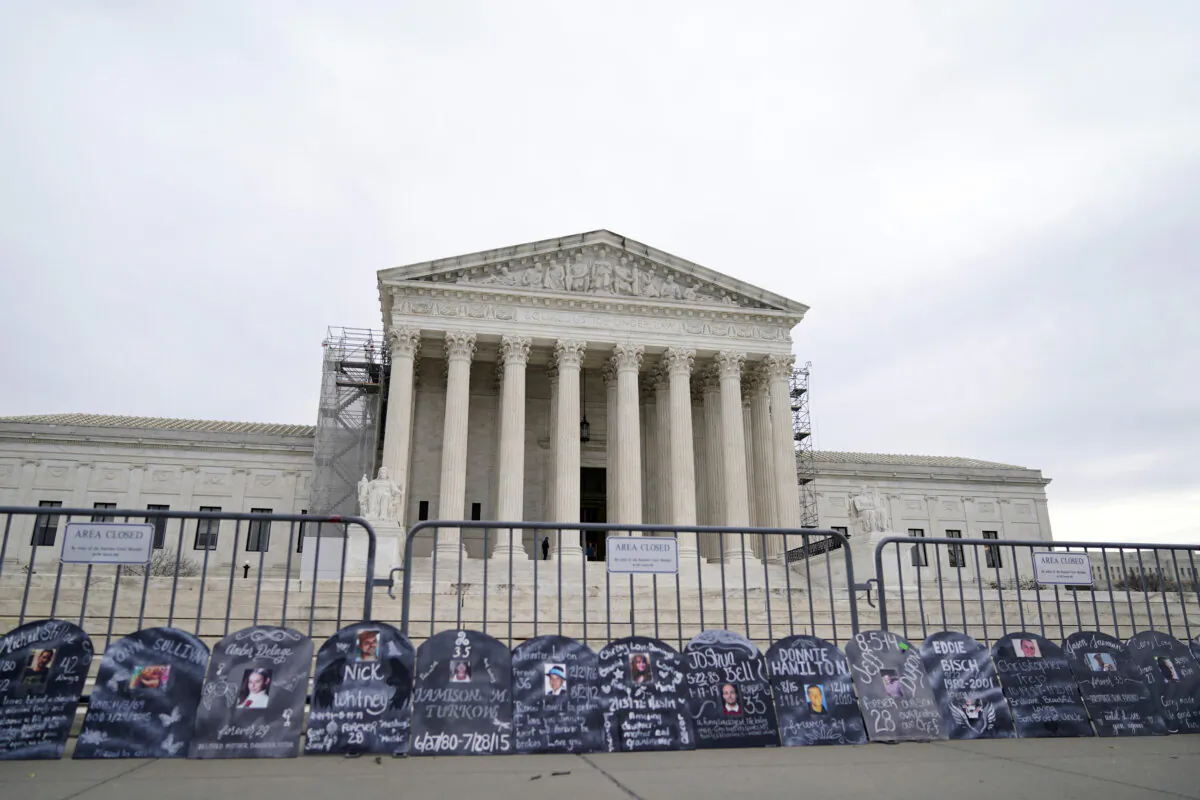 Signs in the shape of grave headstones, with information on people who died from using OxyContin, line a security fence outside the Supreme Court in Washington on Dec. 4, 2023. (Stephanie Scarbrough/AP Photo)