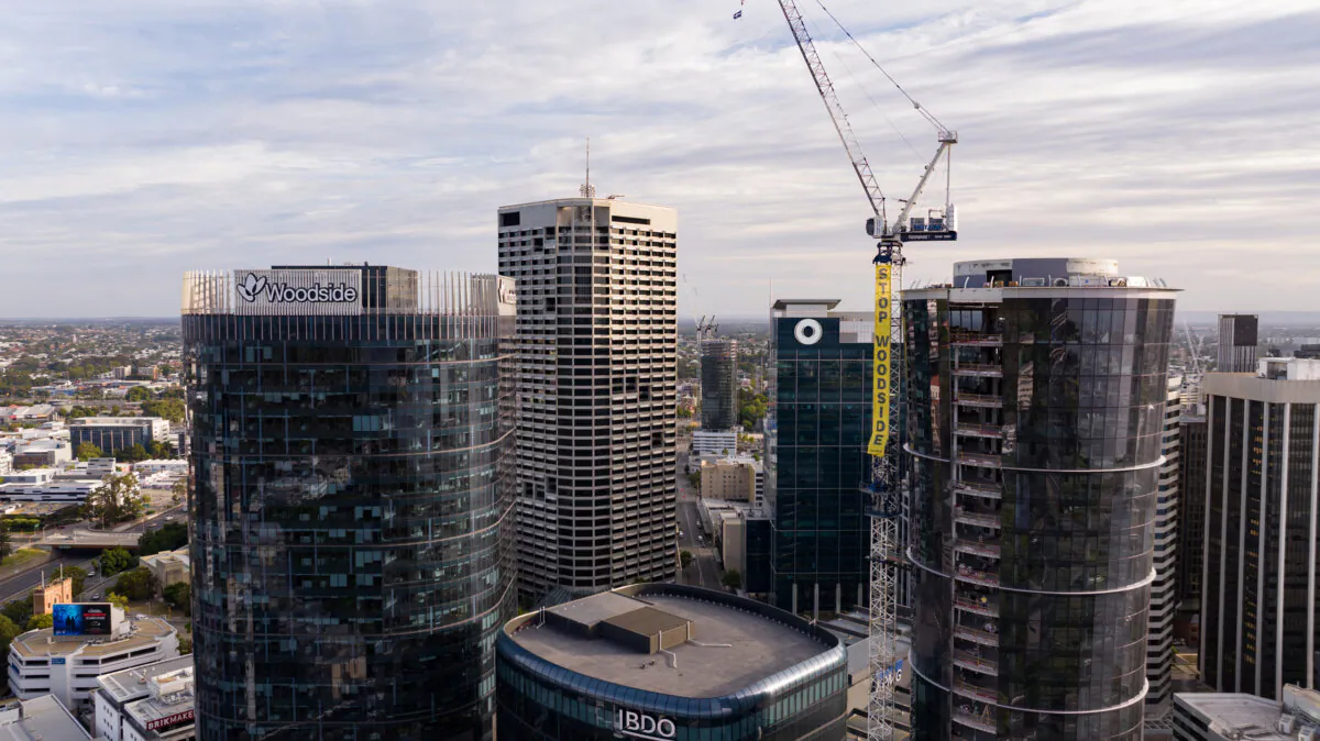 A supplied image shows a Greenpeace protest banner dropped from a crane next to the Woodside headquarters in Perth, Australia on Dec. 5, 2023. (AAP Image/Supplied by Greenpeace)