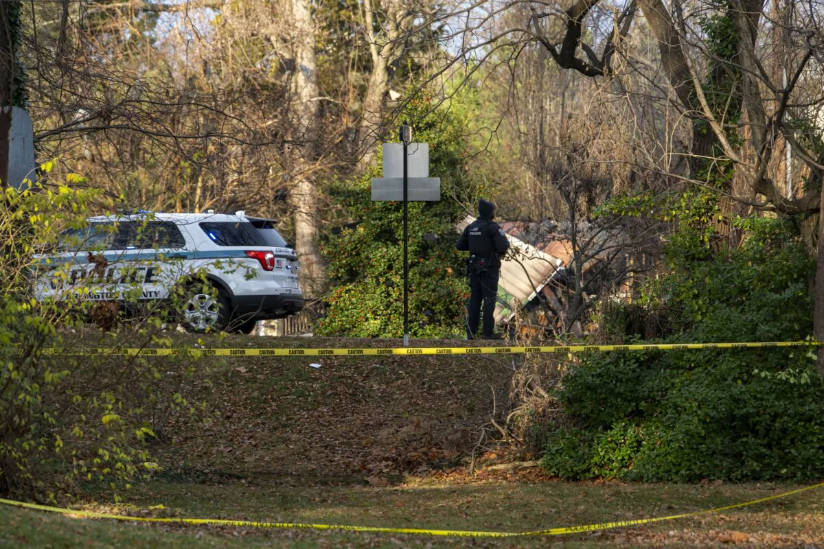 A member of the Arlington County Police Department looks towards the remains of a house explosion in Arlington, Va., on Dec. 5, 2023. (Kevin Wolf/AP Photo)