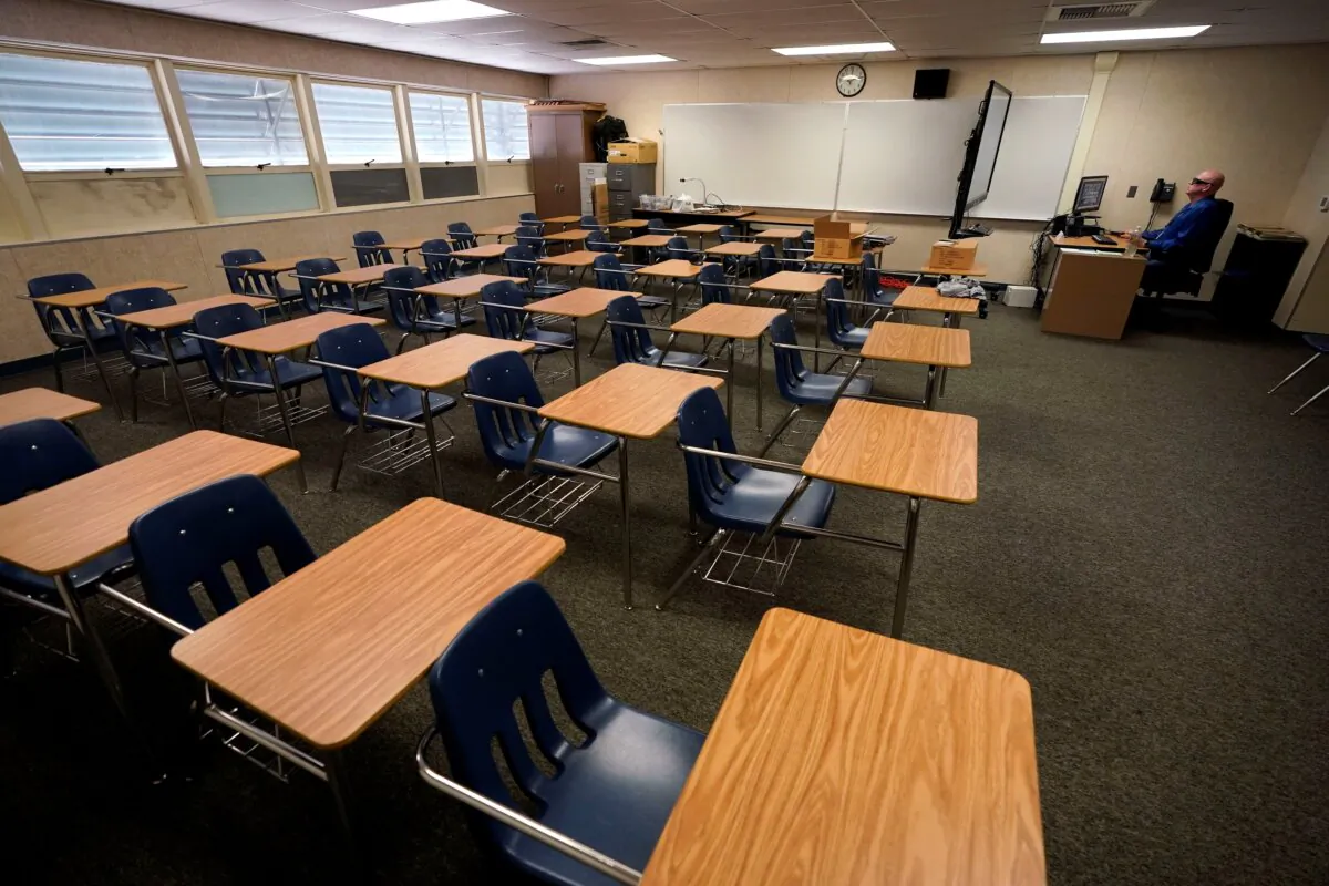 Math teacher Doug Walters sits among empty desks as he takes part in a video conference with other teachers to prepare for at-home learning at Twentynine Palms Junior High School in Twentynine Palms, Calif., on Aug. 18, 2020. (Gregory Bull/AP Photo)