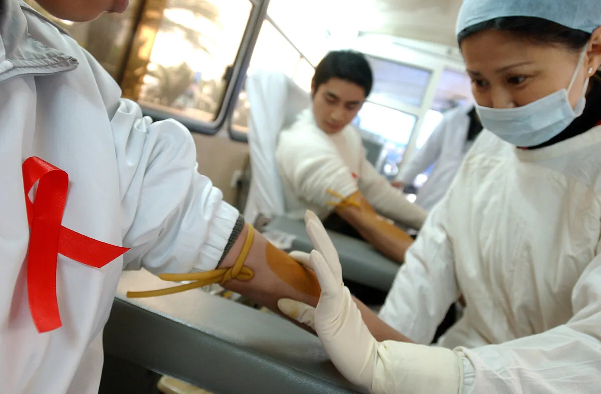 A nurse prepares to collect blood from a donor during a volunteer blood donation campaign to mark World AIDS Day in Chengdu, China, on Dec. 1, 2005. (China Photos/Getty Images)