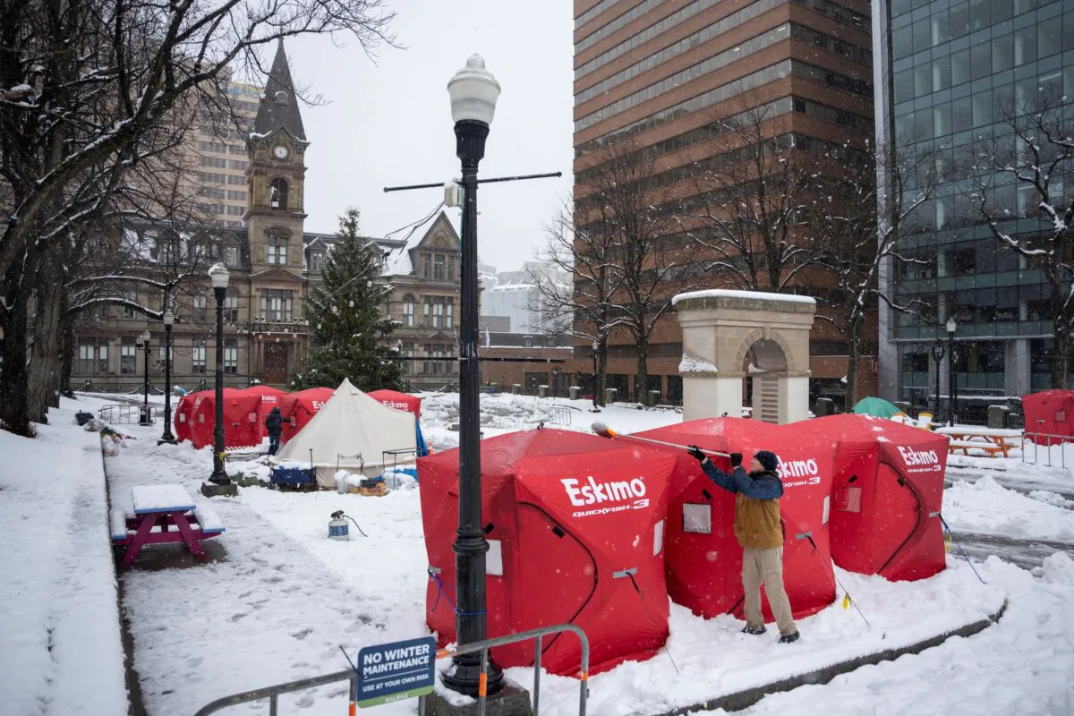 A man clears snow off an enclosure at an encampment in front of City Hall in downtown Halifax, Dec. 4, 2023. (The Canadian Press/Darren Calabrese)