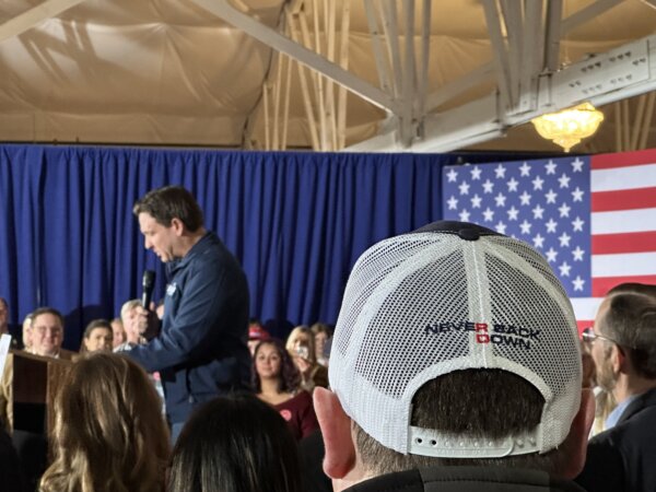 A Ron DeSantis supporter wears a Never Back Down hat while watching the Florida governor speak.