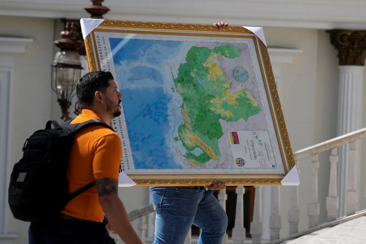 A man carries the new map of Venezuela with the Essequibo territory, a large swath of land that is administered and controlled by Guyana but claimed by Venezuela, to the National Assembly building in Caracas, Venezuela, on Dec. 6, 2023. (Ariana Cubillos/AP Photo)