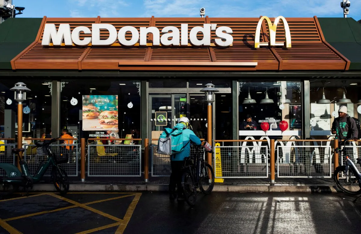 A Deliveroo rider stands beside a bicycle outside a McDonald's restaurant in London on Dec. 10, 2021. (May James/Reuters)
