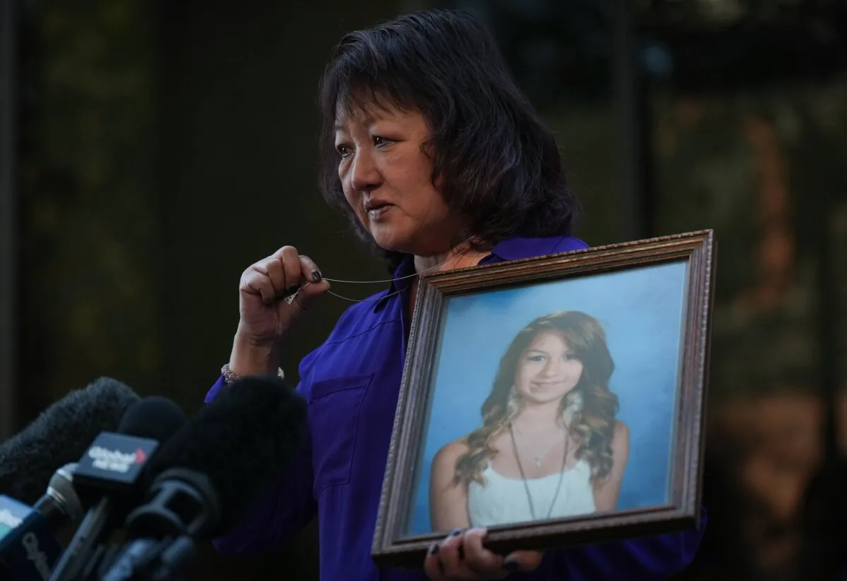 Carol Todd holds a photo of her late teenage daughter Amanda Todd, who died by suicide in 2012, and the necklace she was wearing in the school photo as she speaks outside B.C. Supreme Court after sentencing for the Dutch man who was accused of extorting and harassing her daughter, in New Westminster, B.C., on Oct. 14, 2022. (The Canadian Press/Darryl Dyck)