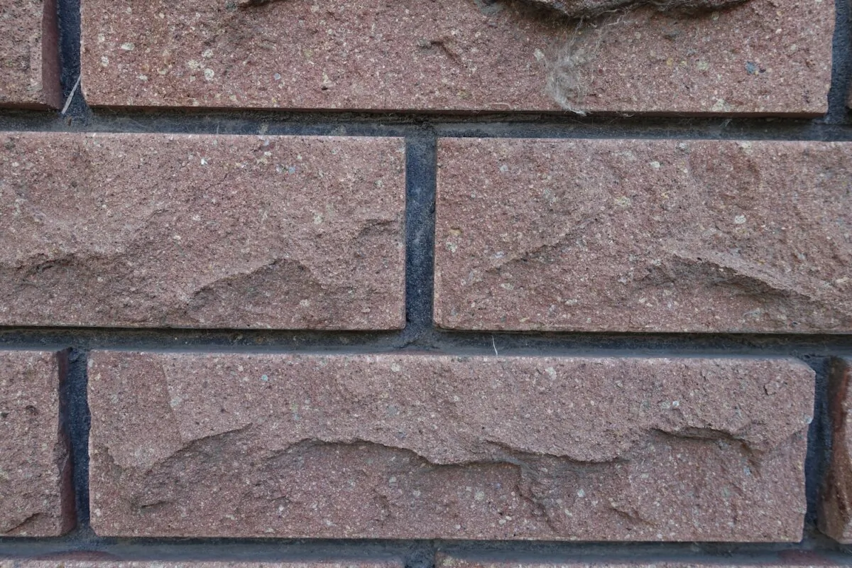 Closeup of brown brick veneer wall with black mortar joints. (APugach/Shutterstock)