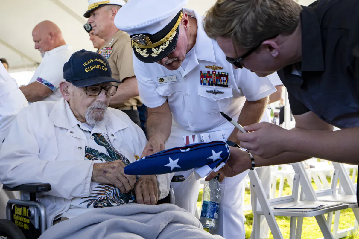An attendee asks Pearl Harbor survivor Ira "Ike" Schab, 103, to sign an U.S. flag during the 82nd Pearl Harbor Remembrance Day ceremony at Pearl Harbor in Honolulu, Hawaii, on Dec. 7, 2023. (Mengshin Lin/AP Photo)