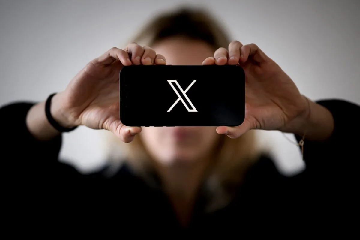 A woman holds a smartphone displaying the logo of US social network X (former Twitter), in Nantes, western France, on Nov. 29, 2023. (Loic Venance/AFP via Getty Images)