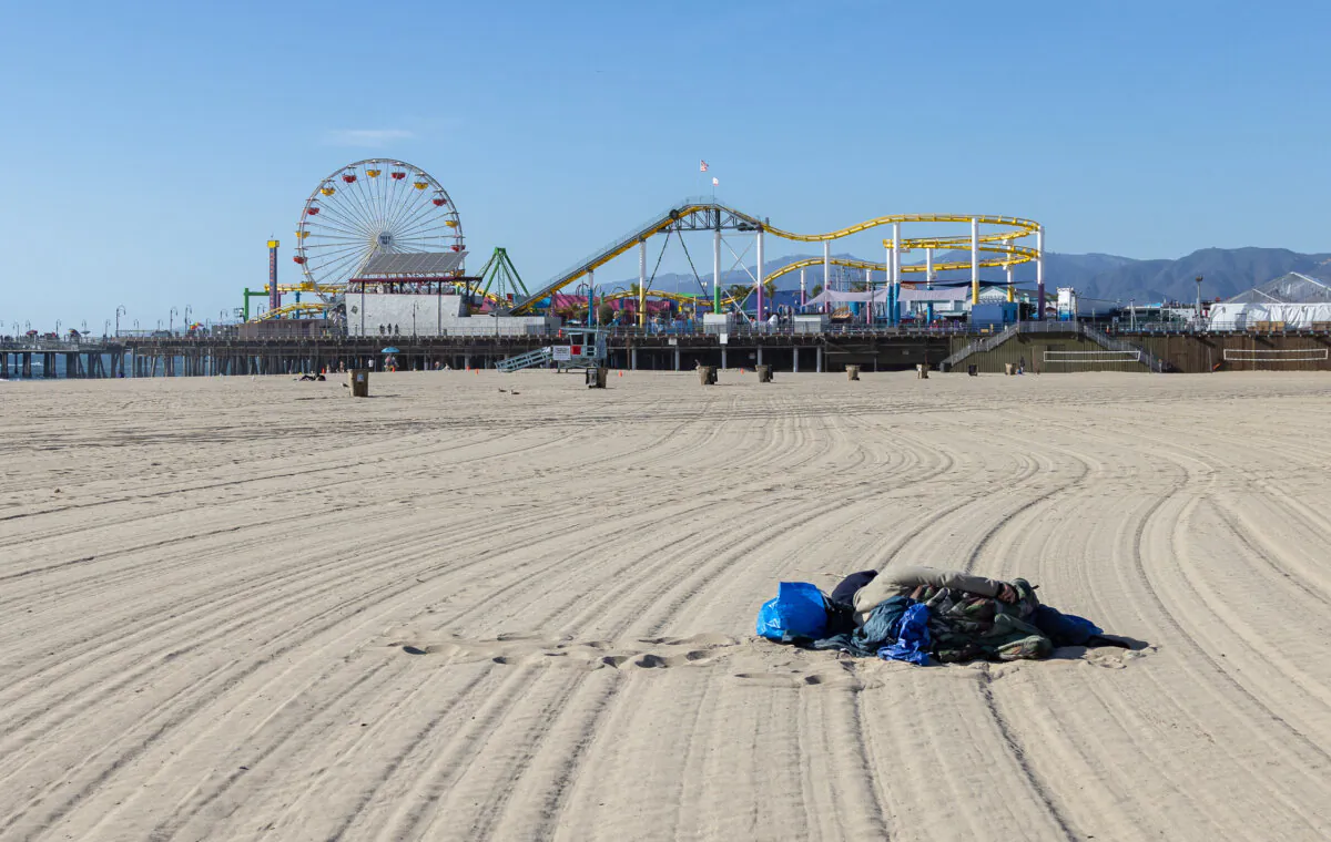 A homeless individual sleeps on the beach in Santa Monica, Calif., in this file photo. (John Fredricks/The Epoch Times)