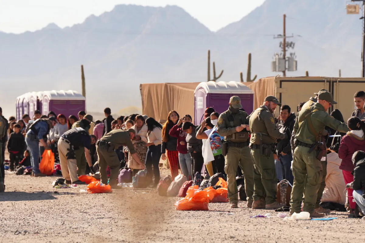 A crowd of illegal aliens wait to board buses to take them to welcome centers in Arizona near the temporarily closed Lukeville Port of Entry on Dec. 7, 2023. (Allan Stein/The Epoch Times)