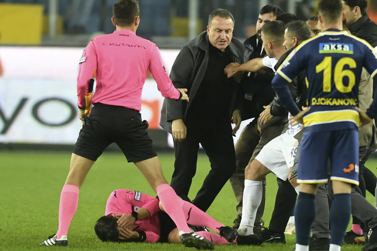 Referee Halil Umut Meler holds his face as he lies on the ground after being punched by MKE Ankaragucu president Faruk Koca (C) at the end of the Turkish Super Lig soccer match between MKE Ankaragucu and Caykur Rizespor in Ankara, Turkey, on Dec. 11, 2023. (Abdurrahman Antakyali/Depo Photos via AP)