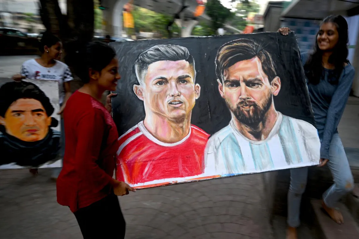 An art school student (L) and her teacher carries a painting of football players Portugal's Christiano Ronaldo (center L) and Argentina's Lionel Messi ahead of the Qatar 2022 World Cup football tournament, in Mumbai on Nov. 18, 2022. (Indranil Mukherjee/AFP via Getty Images)