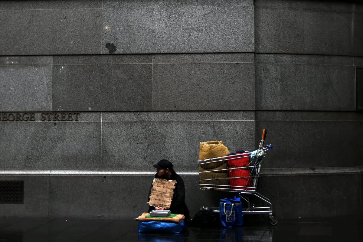 A homeless man waits for charity in the rain in central Sydney, Australia, on May 29, 2020. (Saeed Khan/AFP via Getty Images)