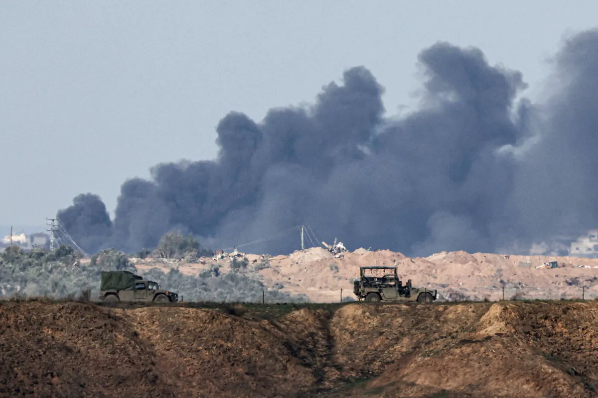Israeli military vehicles drive near the border with the Gaza Strip on Dec. 6, 2023, as black smoke rises in the Palestinian territory amid continuing battles between Israel and the terror group Hamas. (Jack Guez/AFP via Getty Images)