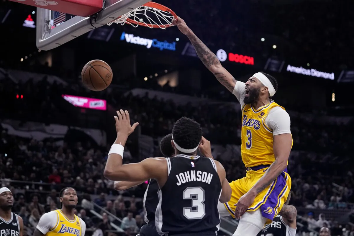 Los Angeles Lakers forward Anthony Davis (3) reacts as he scores over San Antonio Spurs center Victor Wembanyama (1) and forward Keldon Johnson (3) during the first half of an NBA basketball game in San Antonio on Dec. 13, 2023. (Eric Gay/AP Photo)