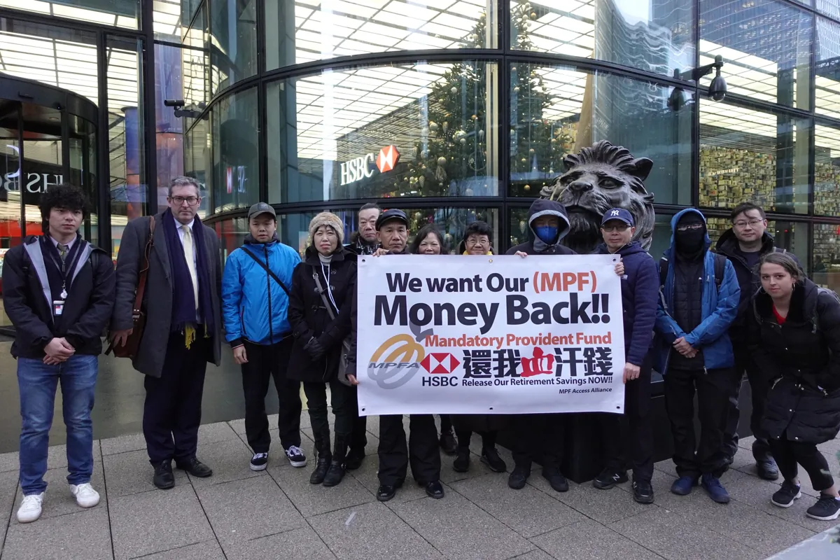 More than a dozen Hong Kong people protested outside the HSBC headquarters to protest against HSBC, one of the trustees of the Mandatory Provident Fund (MPF), for withholding substantial MPF savings belonging to overseas Hongkongers and demanded the return of the funds.  Benedict Rogers (L2), co-founder and Chief Executive of Hong Kong Watch, a human rights organization, was also present to offer their support. London, Dec. 12 . (Bina/The Epoch Times)