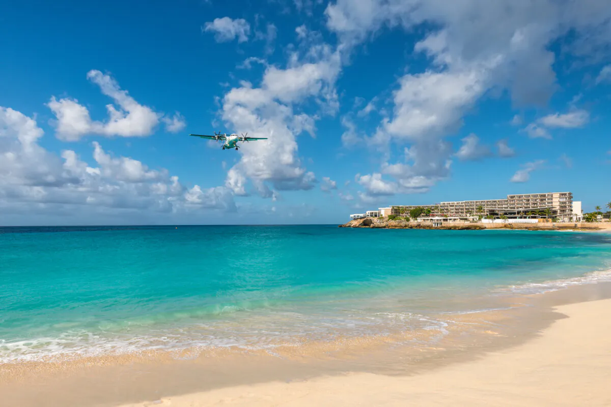 An airplane landing at the Princess Juliana International Airport flying low over water at Maho Beach in Saint Martin, Dutch Antilles, Caribbean. (byvalet/Shutterstock)