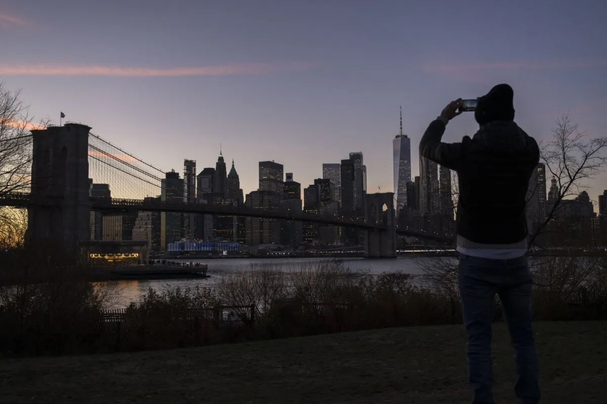 A person takes a picture during sunset in New York on Dec. 14, 2023. (Angela Weiss/AFP via Getty Images)