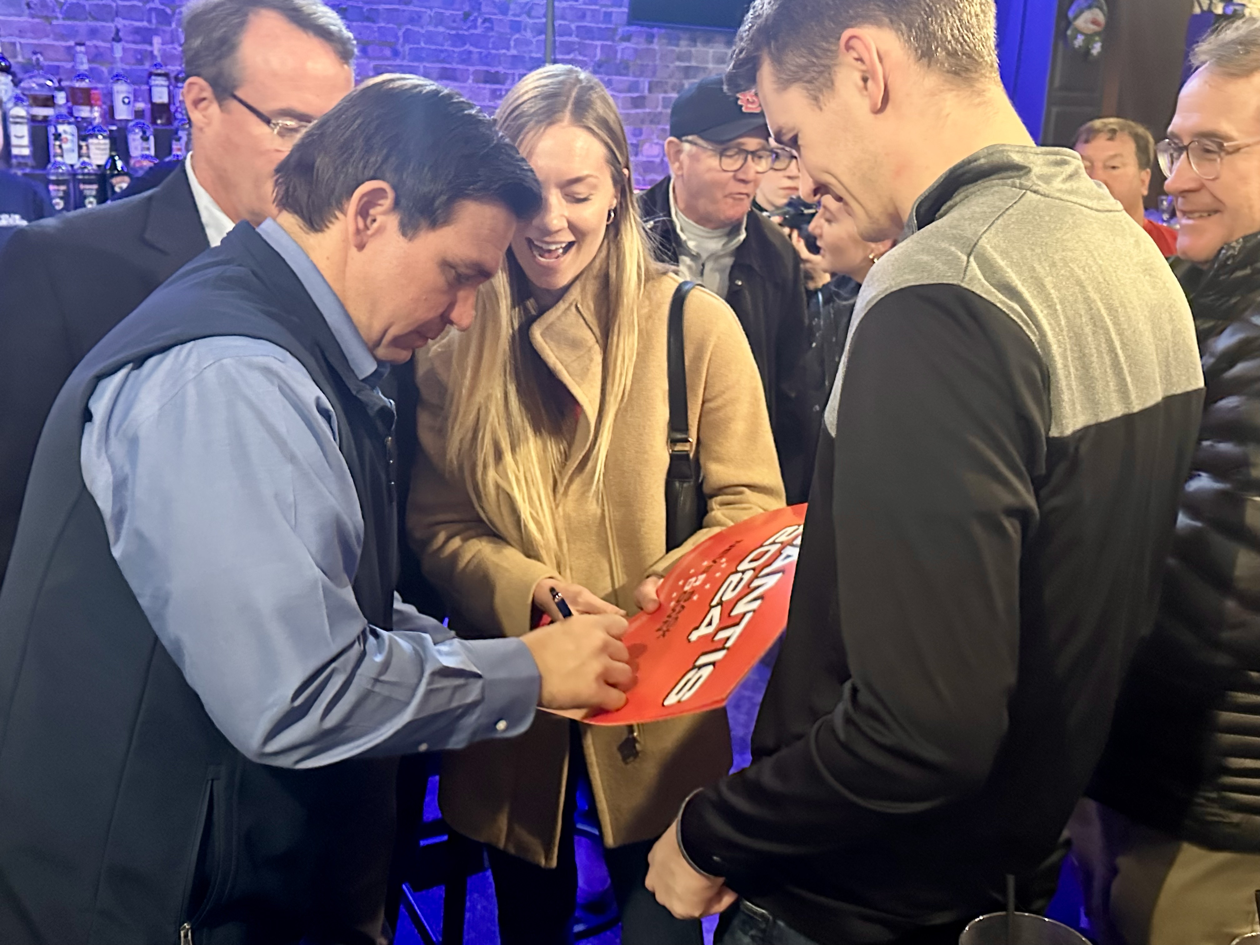 Florida Gov. Ron DeSantis signs a supporter's campaign sign during an event in Ft. Dodge, Iowa, on Saturday, Dec. 16, 2023.