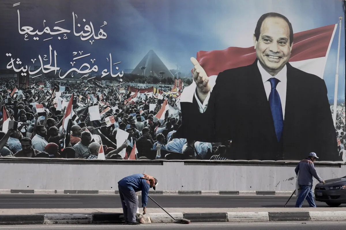 Workers clean the street under a billboard supporting Egyptian President Abdel Fattah el-Sissi for the presidential elections in Cairo on Dec. 10, 2023. (Amr Nabil/AP Photo)