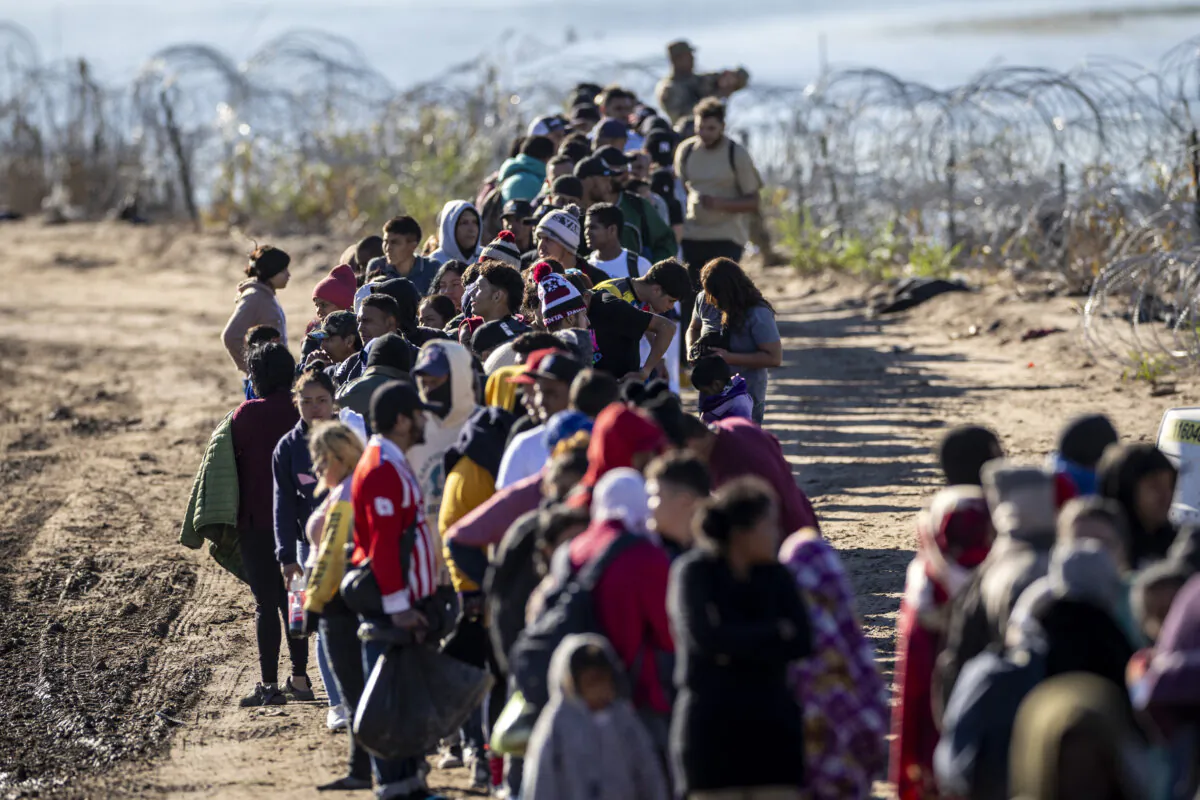 More than 1,000 illegal immigrants wait in line to be processed by U.S. Border Patrol agents after crossing the Rio Grande from Mexico in Eagle Pass, Texas, on Dec. 18, 2023. (John Moore/Getty Images)
