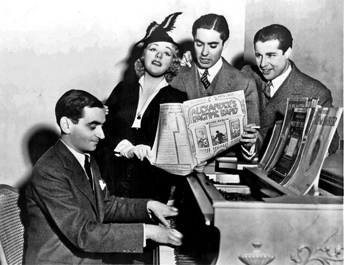 (L-R) Berlin with film stars Alice Faye, Tyrone Power, and Don Ameche singing chorus from "Alexander's Ragtime Band" (1938). (Public Domain)