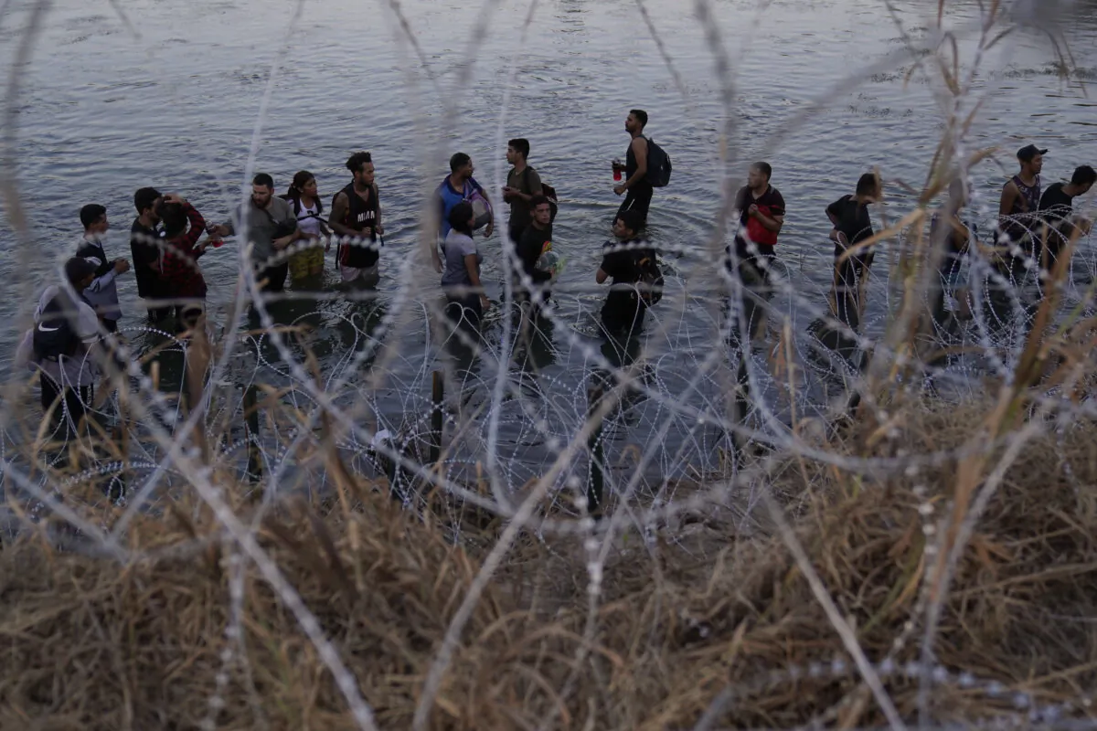 Illegal immigrants wait to climb over concertina wire after they crossed the Rio Grande and entered the United States from Mexico, in Eagle Pass, Texas, on Sept. 23, 2023. (Eric Gay/AP Photo)