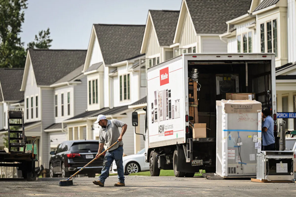 A maintenance worker sweeps the street in front of a row of new homes in Fairfax, Va., on Aug. 22, 2023. (Andrew Caballero-Reynolds/AFP via Getty Images)