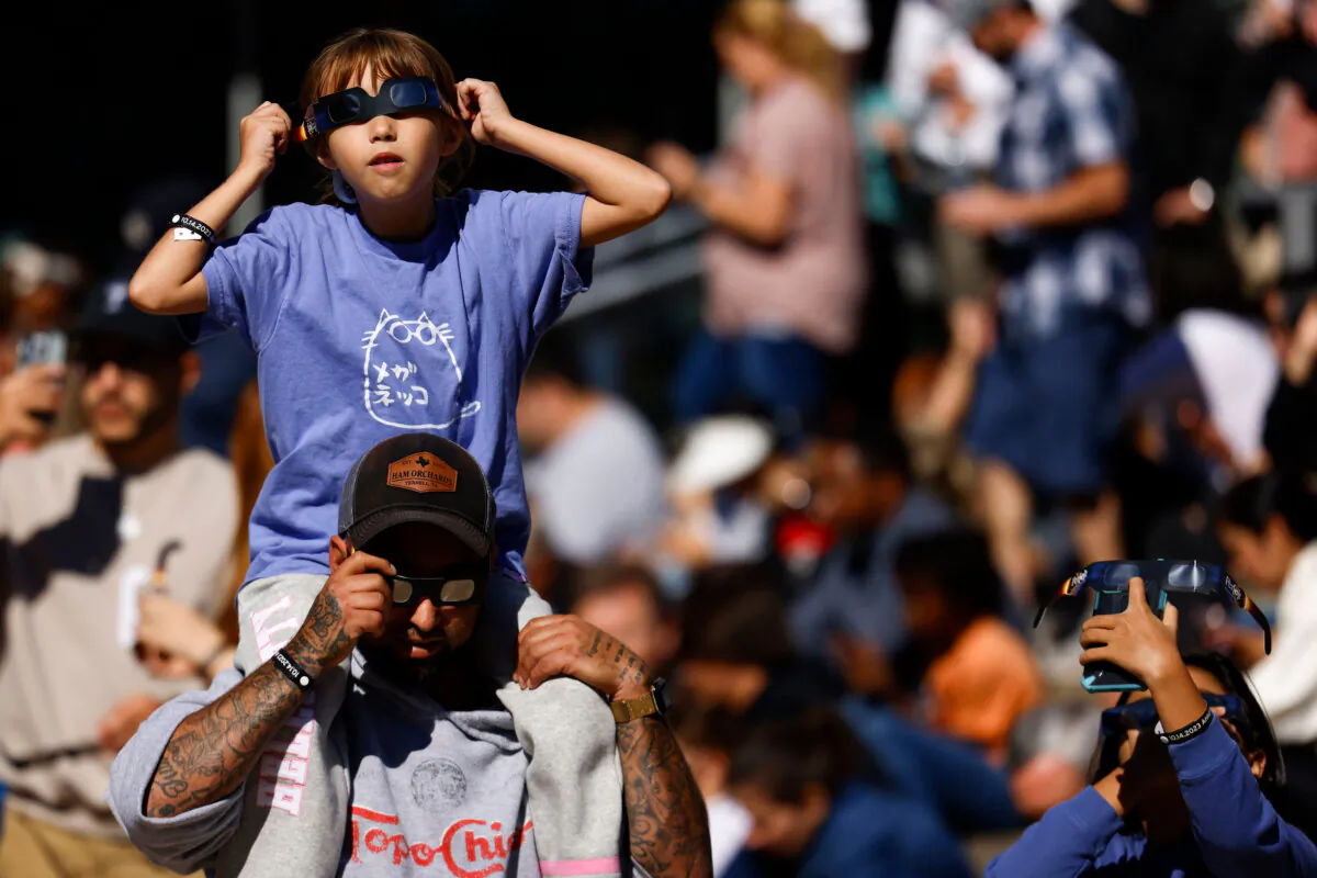 William Casarez carrying his daughter Brianna, 9, watch the annular solar eclipse on Oct. 14, 2023, at Perot Museum of Nature and Science in Dallas. (Shafkat Anowar/The Dallas Morning News/TNS)