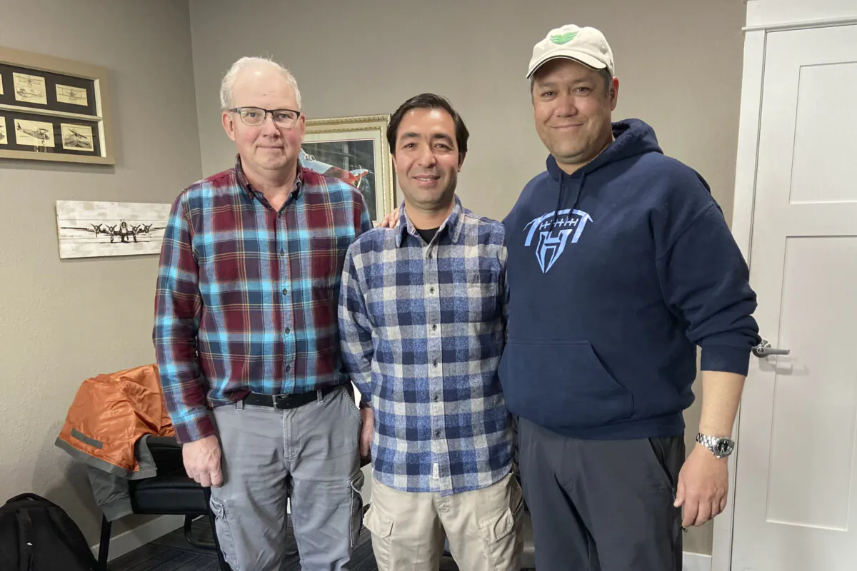 Mohammad Hussain Musawi (C) stands with his flight instructor (L) and Darin Chung, co-founder of the Afghan American Development Group, a nonprofit that helps former Afghan military aviation personnel with refugee resettlement assistance in the United States, at a flight hangar in Independence, Ore., on April 7, 2023. (Nikki Chung via AP)