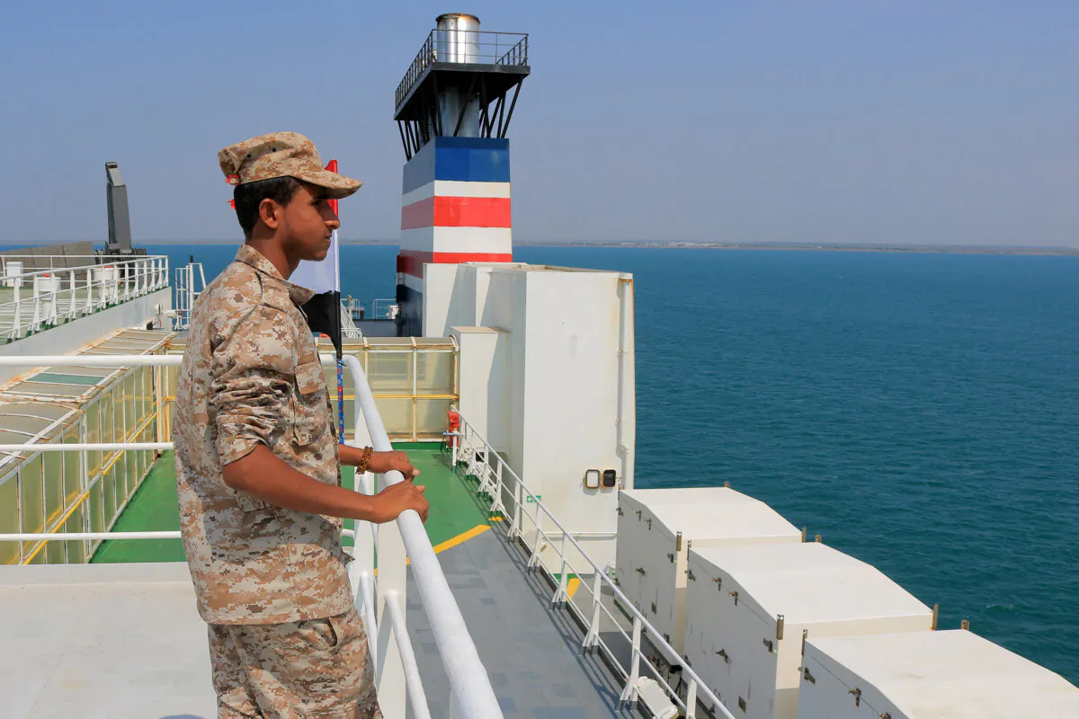 A picture taken during an organized tour by Yemen's Huthi rebels on November 22, 2023 shows a security guard aboard the Galaxy Leader cargo ship, seized by Huthi fighters two days earlier, in a port on the Red Sea in the Yemeni province of Hodeida, with Palestinian and Yemeni flags installed on it. (AFP via Getty Images)