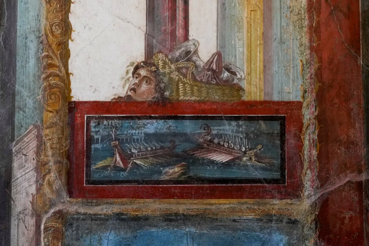 A detail of a fresco showing a sea battle framed in Pompeii red topped by a basket and a mask that decorates the living room of house of the Vetti, in one of the wealthiest homes in Pompeii, the House of the Vetti, in the Pompeii archeological site, Italy, on Dec. 7, 2023. (Andrew Medichini/AP Photo)