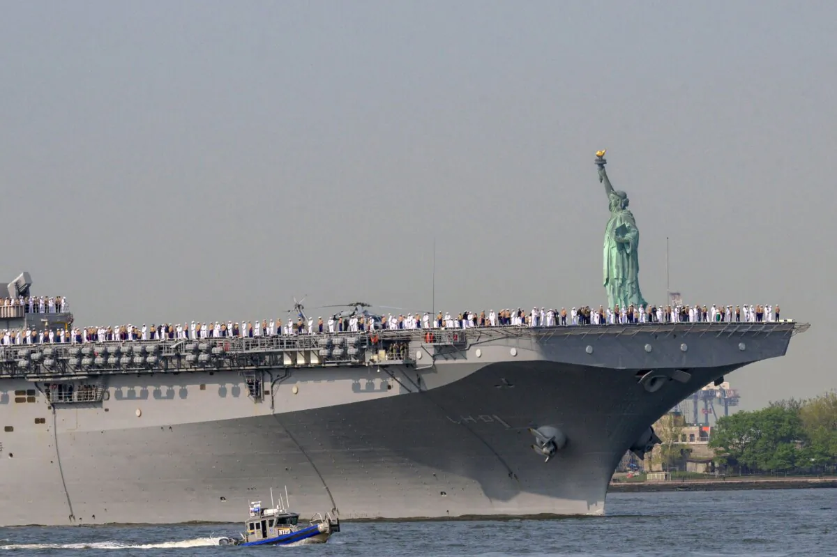 U.S. Sailors and Marines stand on the flight deck of the USS Bataan, a Wasp-class amphibious assault ship, as it passes the Statue of Liberty during Fleet Week in New York Harbor on May 24, 2023. (Angela Weiss/AFP via Getty Images)