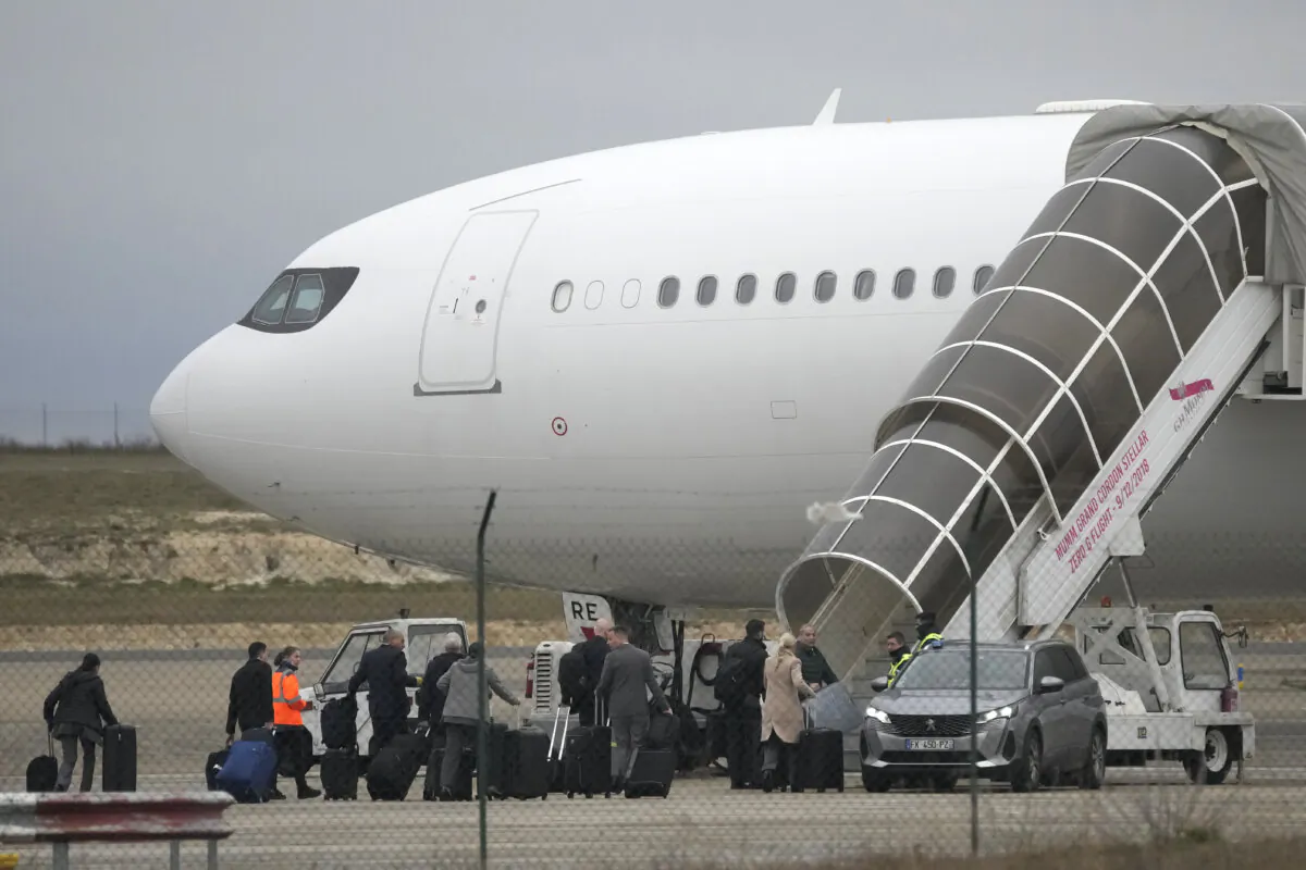 Crew members board the plane grounded by police at the Vatry airport, in Vatry, eastern France, on Dec. 25, 2023. (Christophe Ena/AP Photo)