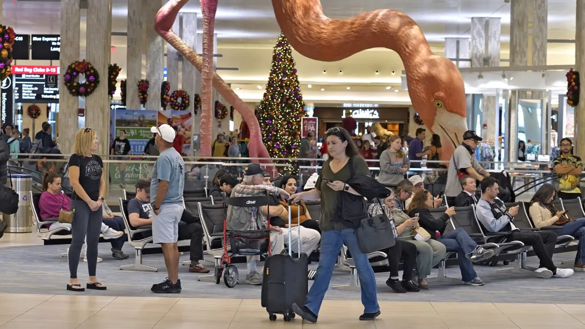 Holiday travelers pass by "Phoebe" the Flamingo at the Tampa International Airport in Tampa, Fla., on Dec. 22, 2023. (Chris O'Meara/AP Photo)