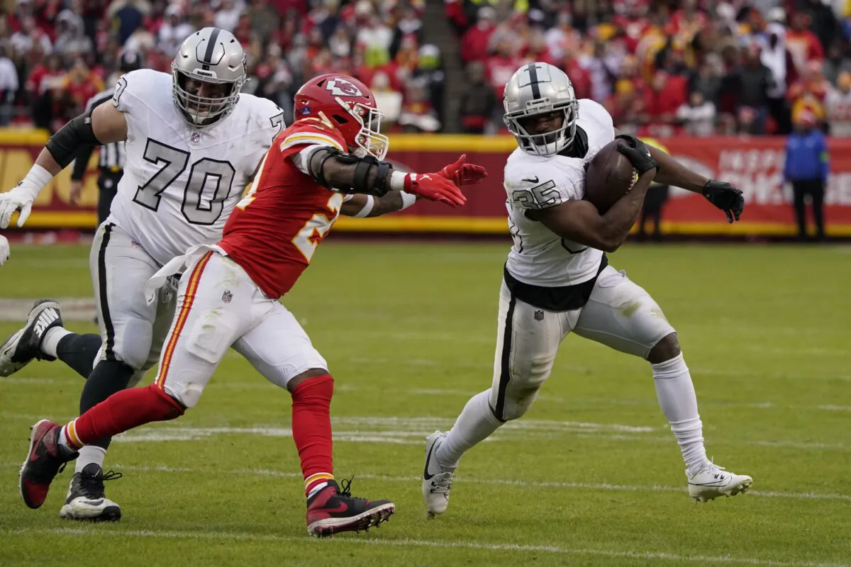 Las Vegas Raiders running back Zamir White (35) runs with the ball as Kansas City Chiefs safety Mike Edwards defends and Raiders guard Greg Van Roten looks on during the second half of an NFL football game in Kansas City on Dec. 25, 2023. (Ed Zurga/AP Photo)