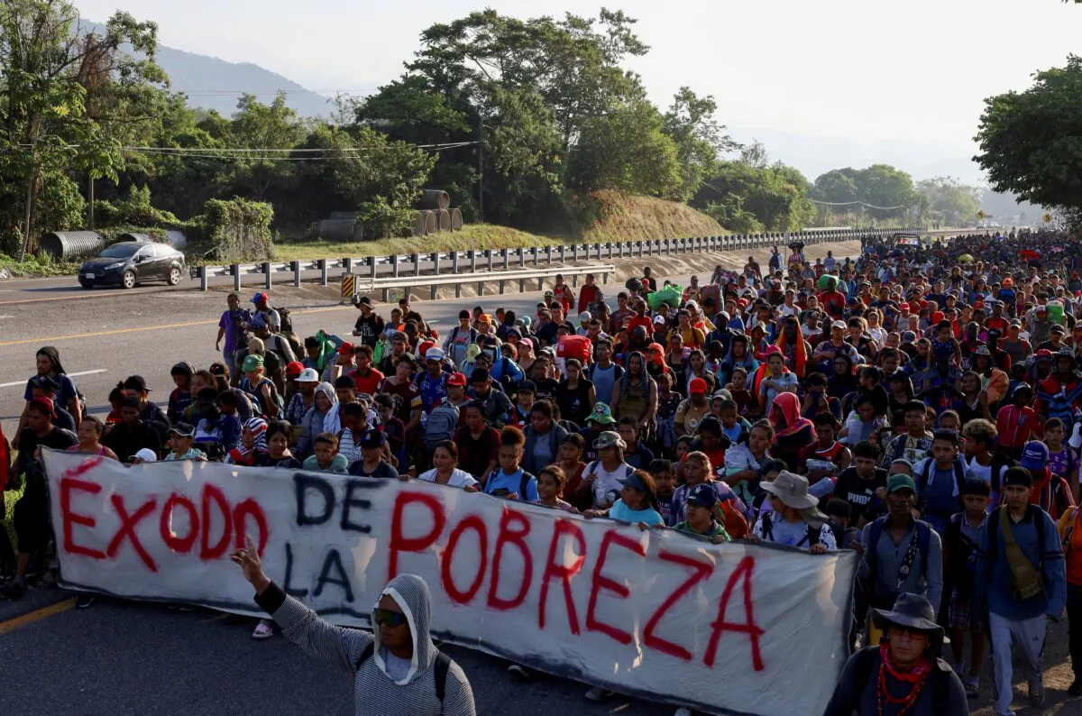 Migrants walk in a caravan, some of them holding a banner reading "Exodus from Poverty," as an attempt to reach the U.S. border, in Huixtla, Mexico, on Dec. 26, 2023. (Jose Torres/Reuters)
