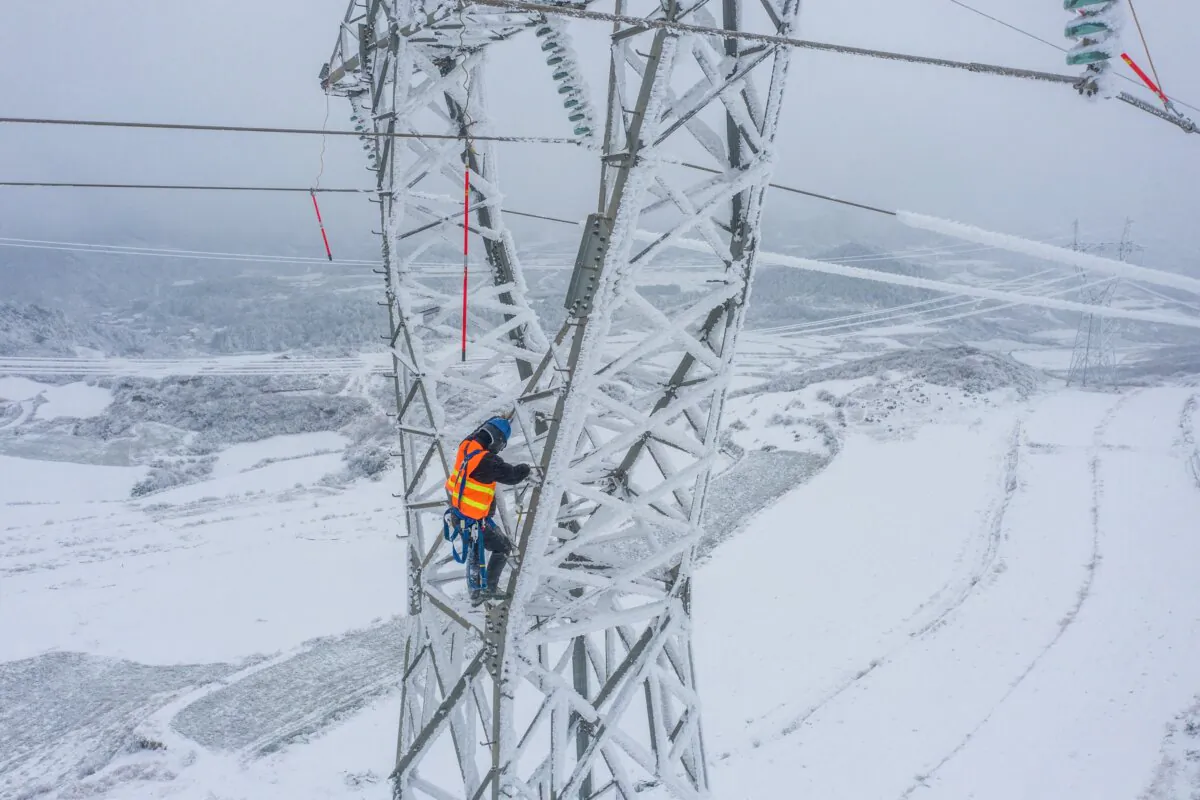 A worker climbs a pylon to remove ice from electric transmission lines in Bijie, in China's southwestern Guizhou province, on Feb. 21, 2022. (STR/AFP via Getty Images)