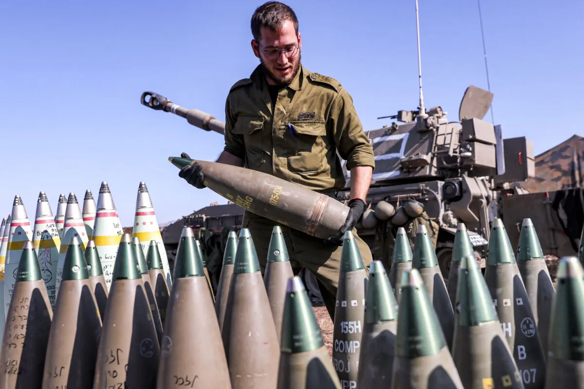 An Israeli army soldier carries a 155mm artillery shell near a self-propelled howitzer deployed at a position near the border with Lebanon in the upper Galilee region of northern Israel on Oct. 18, 2023. (Jalaa Marey/AFP via Getty Images)