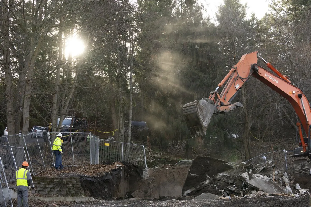 Sunlight breaks through trees as heavy equipment works to demolish the final pieces of the foundation of the house where four University of Idaho students were killed in 2022, in Moscow, Idaho, on Dec. 28, 2023. (Ted S. Warren/AP Photo)