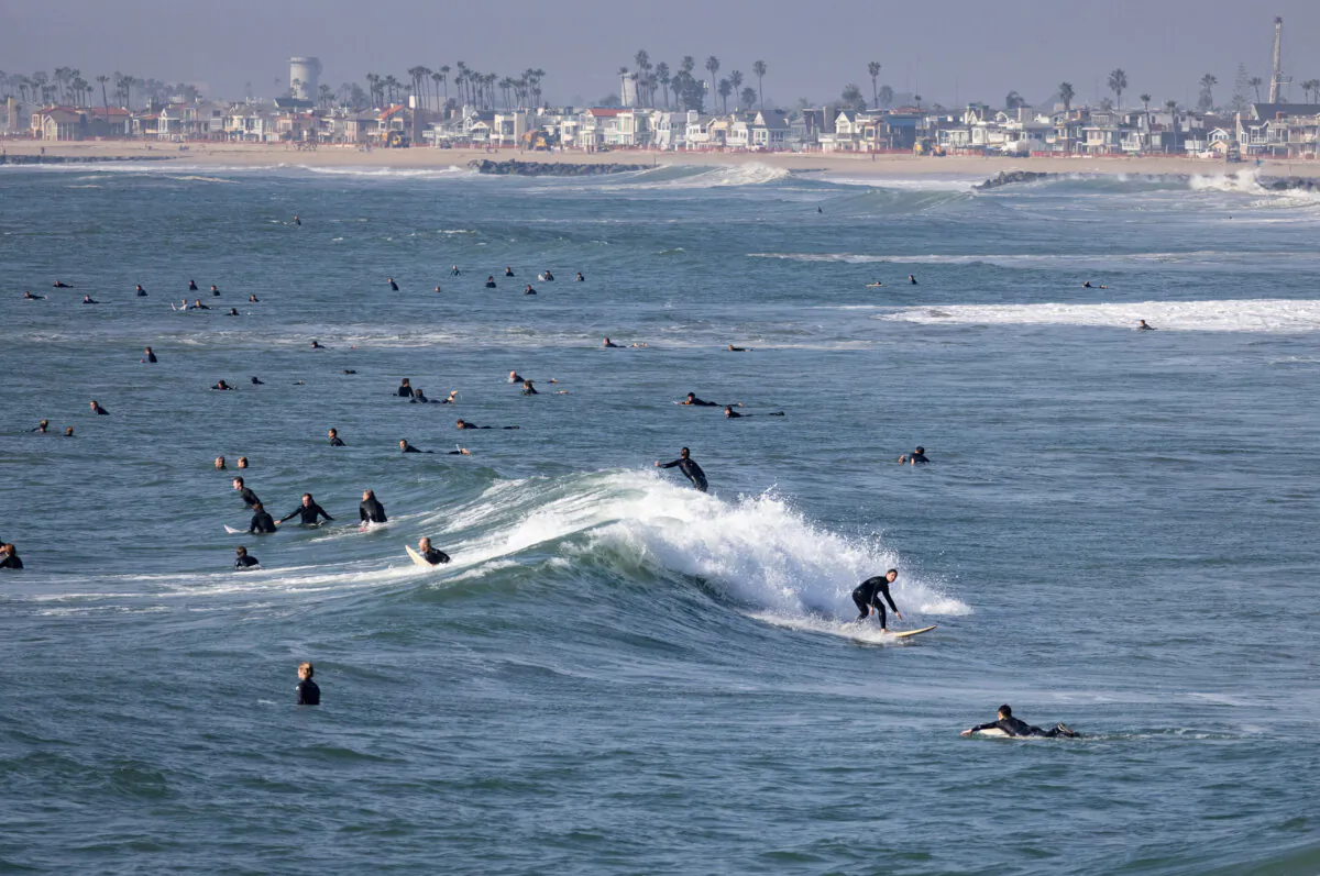 Beachgoers and surfers enjoy high surf conditions in Newport Beach, Calif., on Dec. 28, 2023. (John Fredricks/The Epoch Times)
