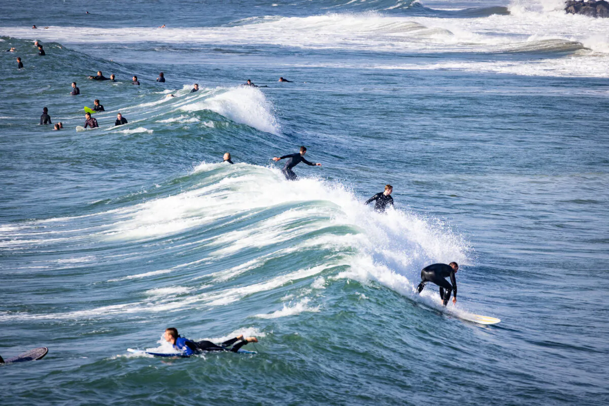 Beachgoers and surfers enjoy high surf conditions in Newport Beach, Calif., on Dec. 28, 2023. (John Fredricks/The Epoch Times)