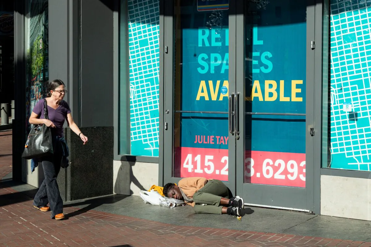 A person sleeps in front of a vacant retail space on Market Street in San Francisco on Nov. 13, 2023. (Jason Henry/AFP via Getty Images)
