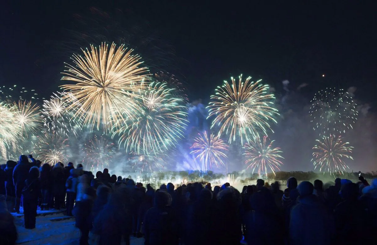 People look on as fireworks explode over Montreal's Old Port during New Years Eve celebrations in Montreal, Jan. 1, 2018. (The Canadian Press/Graham Hughes)