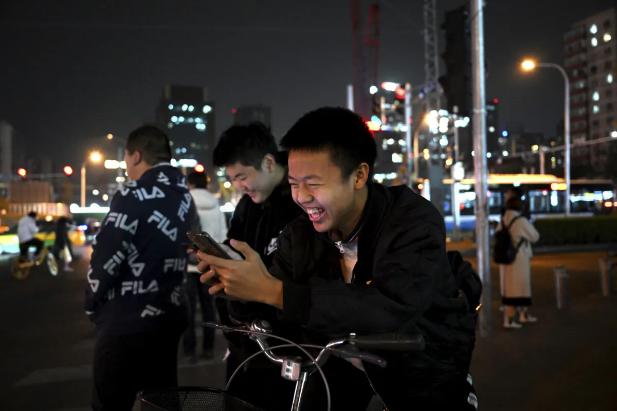 Students play video games on their phones as they wait at an intersection during rush hour in Beijing, China, on Nov. 15, 2023. (Kevin Frayer/Getty Images)